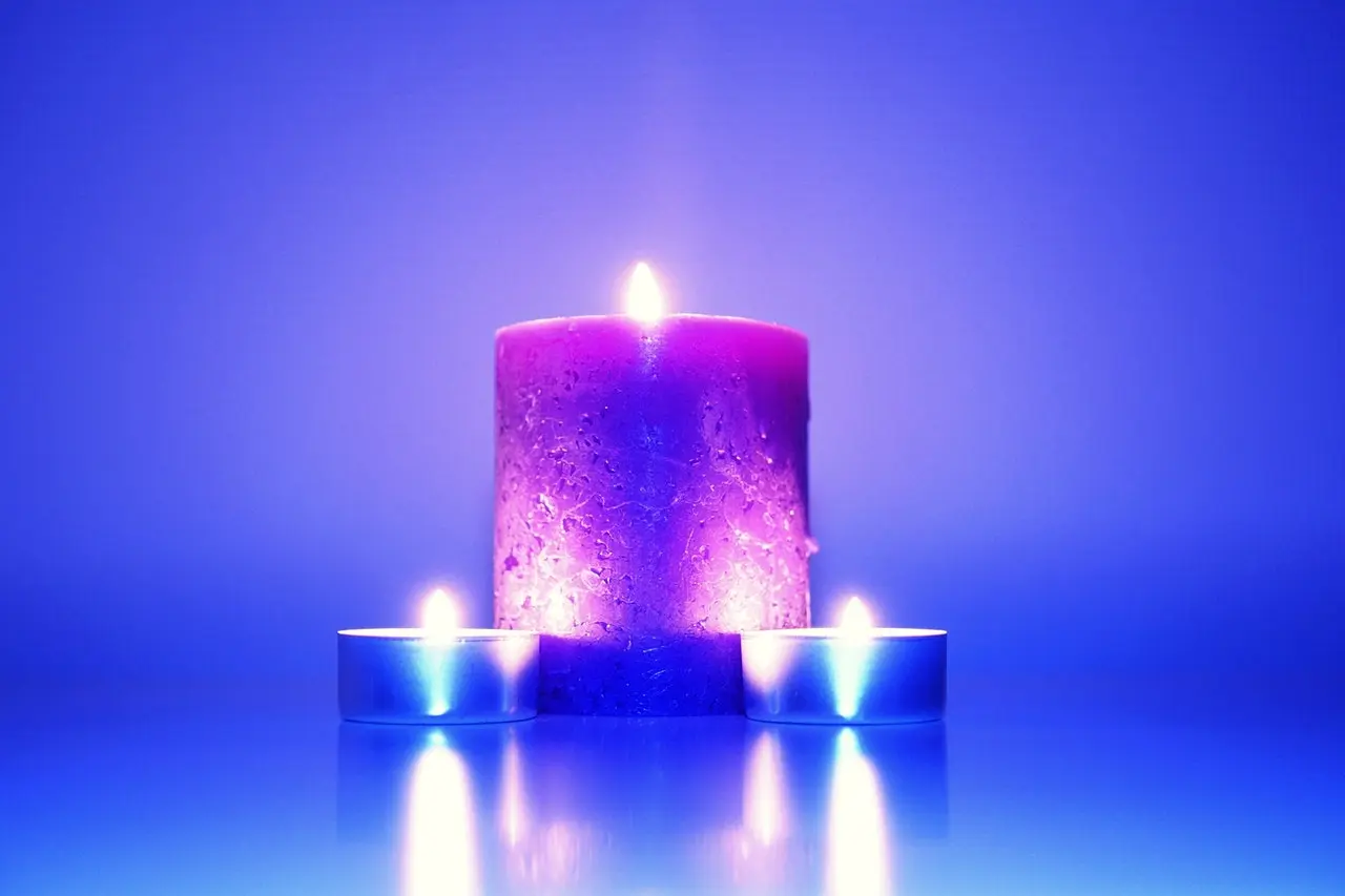 três velas de cores lindas, azuladas e arosadas, com a vela do meio sendo maior que duas dos lados