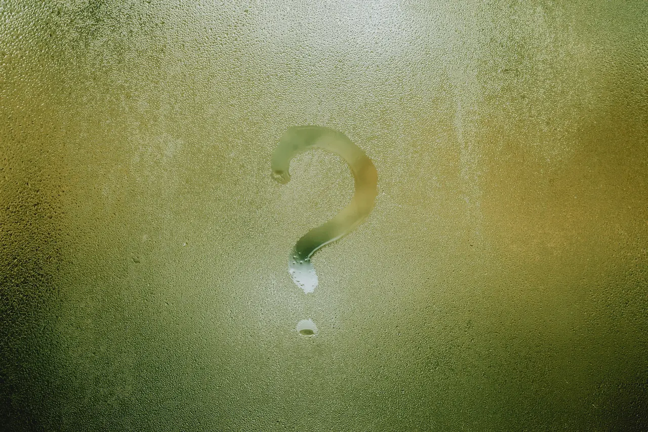 a question mark drawn of a foggy window glass that has rain particles