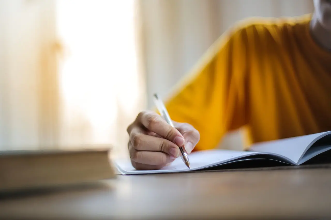 yellow shirt person, writing on a book